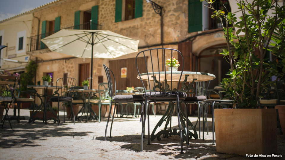 Una terraza de Palma de Mallorca en una soleada tarde de verano. Se ve una sombrilla y algunas mesas y sillas de la terraza del bar.