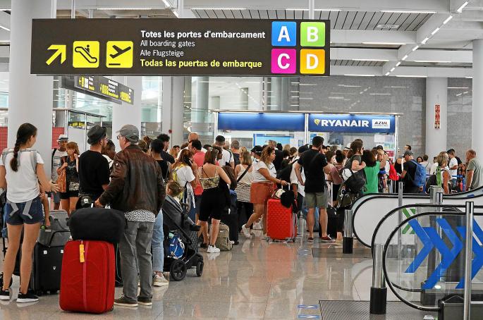 Imagen del aeropuerto de Palma, repleto de pasajeros esperando para facturar, con un cartel de Ryanair al fondo. Indemnización vuelo anulado